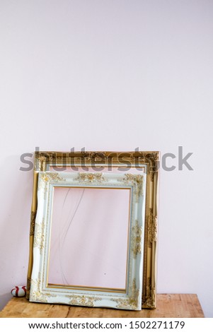 Decoration : Antique White and golden frame isolated on small table in white background, blank picture frame placed on wooden desk . Vintage style