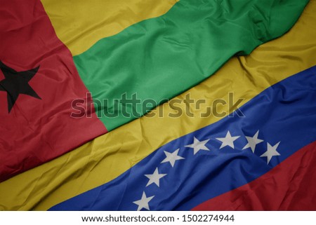waving colorful flag of venezuela and national flag of guinea bissau. macro
