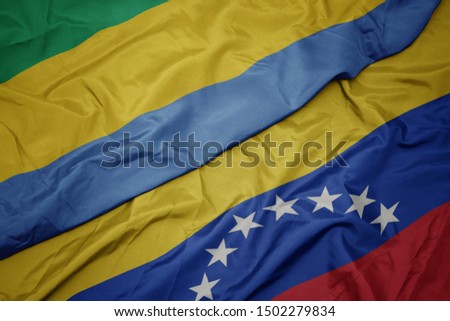 waving colorful flag of venezuela and national flag of gabon. macro