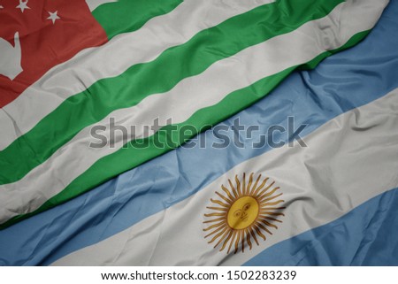 waving colorful flag of argentina and national flag of abkhazia. macro