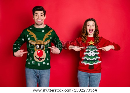 Look! Midnight presents! Portrait of two brunet hair  lovers people scream wow omg point indexf inger his her reindeer christmas tree pattern pullovers wear jeans isolated over red color background