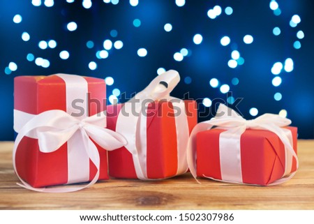 Small christmas gift boxes on wooden table against bokeh lights background