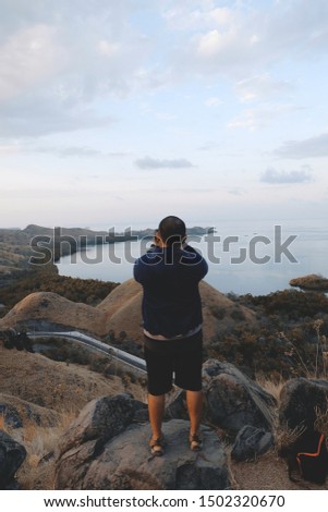A man stands taking pictures of islands in a tourist attraction in Labuan Bajo