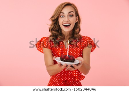 Image of cheery positive happy young woman posing isolated over pink wall background holding birthday cake.