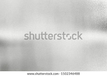 Glowing silver foil metal plate with scratched surface, abstract texture background