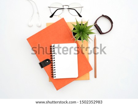 Flat lay black to school and education concept on white table desk with blank notepad and stack of book , green plant and supplies, Top view with copy space, work space