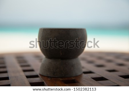 Wooden cup on wooden table with ocean in background