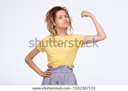 Pretty young asian girl with dreadlocks showing bicep on her arm. Woman power or feminism concept