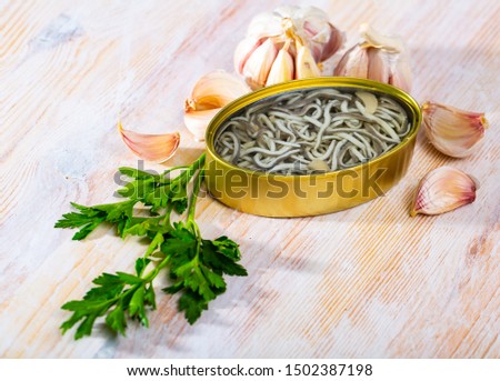 Picture of  tasty pickled  eels on background garlic and greens at table
