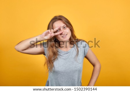 brunette girl in gray t-shirt over isolated orange background shows emotions