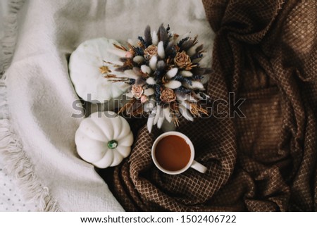 Coffee cup with flowers and pumpkins on a cozy plaid. Autumn still life. Breakfast in bed. Good morning. Stylish autumn flat lay. Hello fall. Cozy warm image
