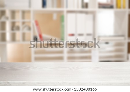 White wooden table top and blurred bookshelf interior background with white light filter - can be used for display or montage your products.