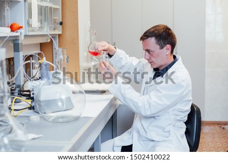 male young scientist conducts chemical experiments with liquids in lab