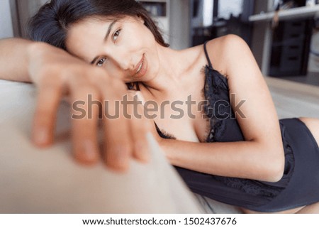 Smiling lady sitting on the floor leaning on her bed