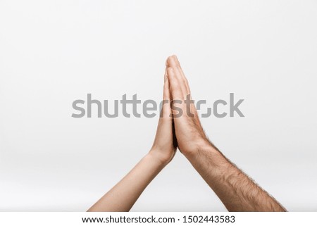 Closeup image of a man's and woman's hands give a high five to each other isolated over white wall background.