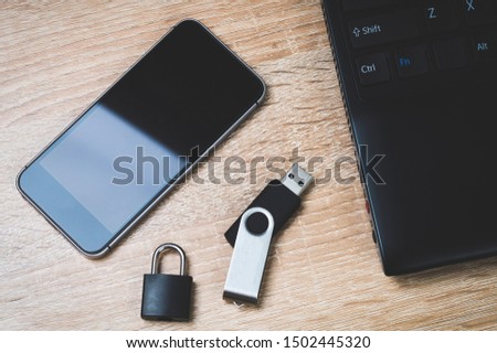 The concept of cybersecurity, black Laptop, black smartphone and USB flash drive, black lock stands on the devices. rendered image