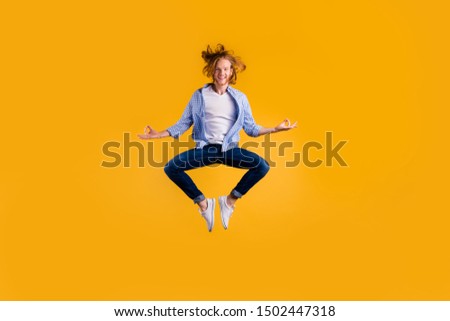 Full length photo of redhead handsome guy jumping high meditating exercise holding body in lotus position wear casual trendy clothes isolated yellow background