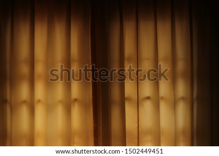 Golden brown curtain with glow of light to use as background.