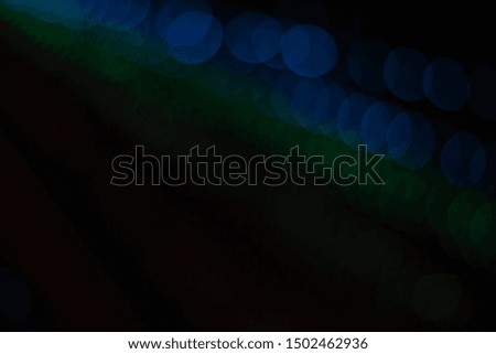 unfocused blurred rays of light green and blue bokeh sparkles from garland in black darkness background Christmas winter holidays moody wallpaper patter picture with empty space for copy or text
