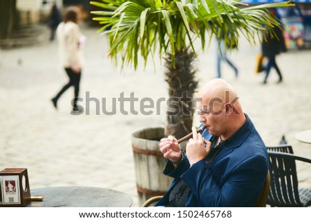 a man sits and  smokes a cuban cigar