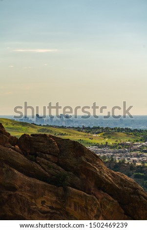 View from the hill on big city with mountains afar. Colorful sunset over bright cityscape. Denver from far away.