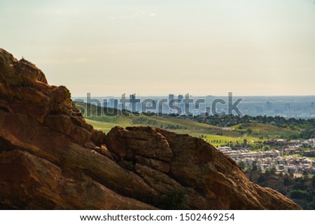 View from the hill on big city with mountains afar. Colorful sunset over bright cityscape. Denver from far away.