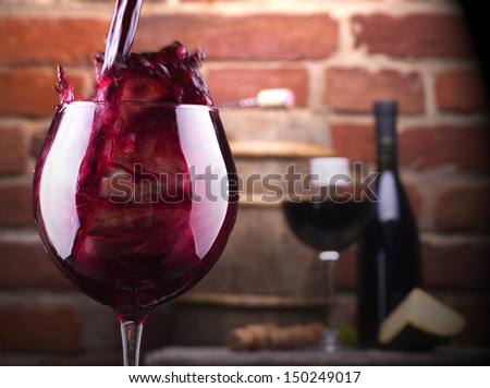 Glass of wine and some fruits, bottle of wine, cheese against a brick wall.