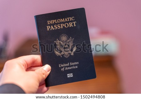 Hand holds up black Diplomatic Passport for the United States of America Royalty-Free Stock Photo #1502494808