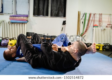 Brazilian Jiu jitsu BJJ jiujitsu training sparring athlete fighter applying arm bar armbar submission on his opponent technique practice wearing kimono gi Royalty-Free Stock Photo #1502514872