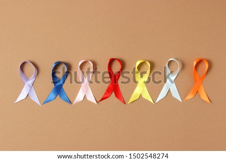 different colors of ribbon on a colored background, international symbol. Cancer disease.
