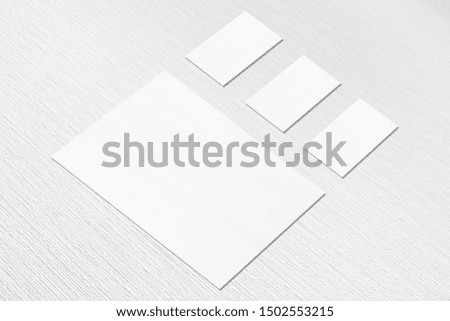 One empty white vertical a4 sized poster and three horizontal rectangle business card mockups with soft shadows on neutral light grey textured background. Flat lay, isometric composition.