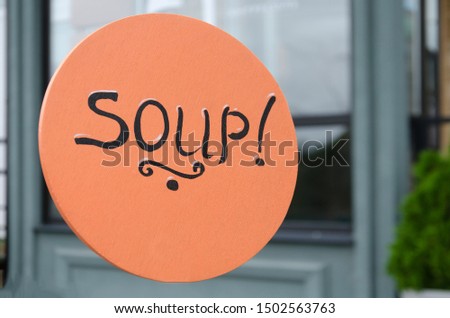 the inscription "soup" is written on an orange wooden plate on the street at lunchtime. delivery of lunch, soups