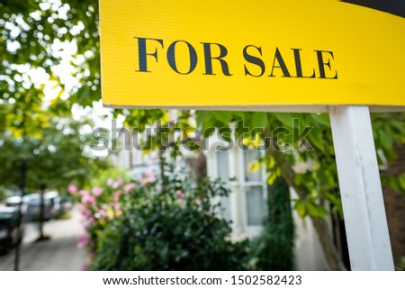 House 'For Sale' sign on suburban street of  houses