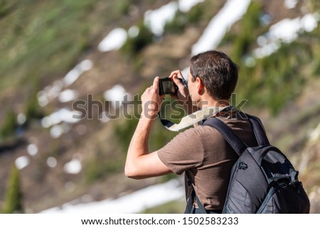Man taking pictures of view on Linkins Lake trail on Independence Pass in rocky mountains near Aspen, Colorado in early summer of 2019 with snow background