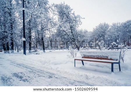 Garden bench in the Park in the winter snowfall. Seasonal phenomenon. Winter snow background