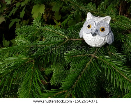 Bauble figurines of owl. Christmas retro sparkle decoration on a spruce branch. Holiday background with a copy space.