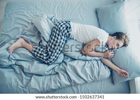 Top above high angle photo of dreamy man lying on bed sleep side  have free time weekends stay in house indoors wear checkered plaid pajama