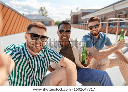 leisure, technology and people concept - happy male friends taking selfie and drinking beer on street in summer
