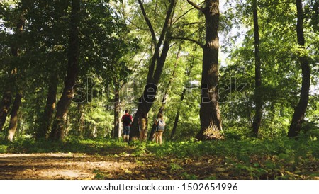 dad and daughters, children travel in park in summer. teamwork travelers. Family on vacation travels in forest. friends-tourists go camping in forest. People walk through trees and grass.