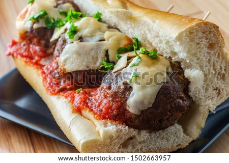 Italian meatball parmesan hero sandwich on a torpedo roll with parsley garnish Royalty-Free Stock Photo #1502663957