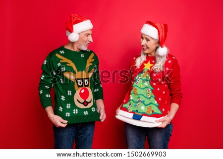 December you are crazy concept. Two excited cheerful positive nice glad friends husband wife people showing each other funky motley comic pictures of reindeer on jumpers isolated color background