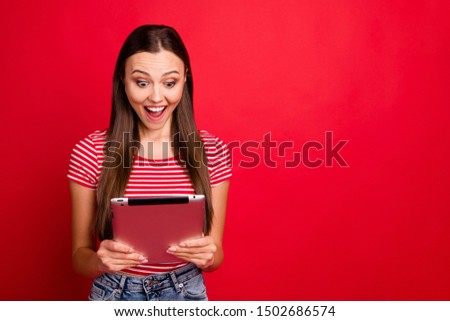 Copyspace photo of amazed beautiful interested girlfriend seeing discounts in her tablet while isolated with red background
