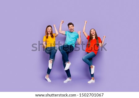 Full body length size photo of cheerful excited ecstatic positive lucky company of fellows having fun raising fists up isolated over violet background