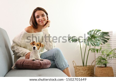 Portrait of young beautiful hipster woman with her adorable four months old jack russell terrier puppy at home in living room full of natural sunlight. Lofty interior background, close up, copy space.
