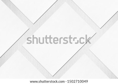 Close up of empty white rectangle poster or card mockups lying diagonally with soft shadow on neutral light grey textured background. Flat lay, top view. Open composition.