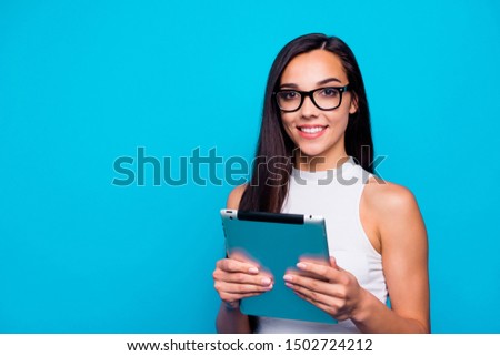 Photo of pretty youngster lady holding e-book in hands ready to listen lecture and make notes wear specs white tank-top isolated blue color background