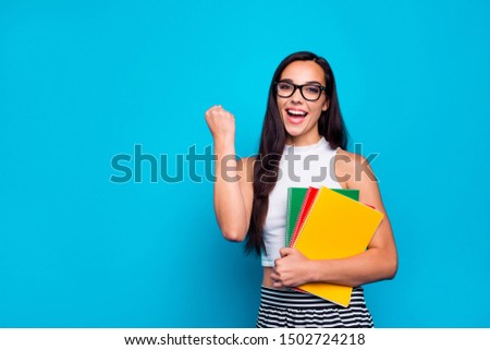 Photo of pretty lady holding study book in arms diligent student celebrating best exam result wear specs white tank-top and striped skirt isolated blue color background