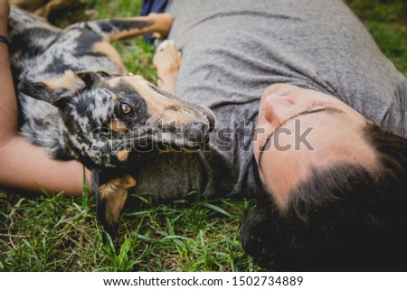 Happy dog and young man laying on the grass - Concepts of friendship, pets, togetherness.