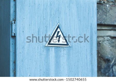 Old blue door with shock hazard sign

