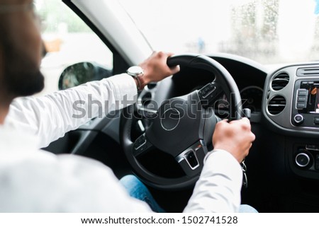 Young handsome man in his car adjusting rear view mirror during day